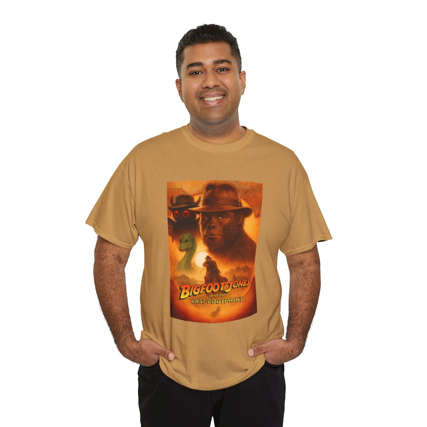 A smiling man in a tan t-shirt with a Bigfoot Jones graphic, standing with his hands in his pockets.